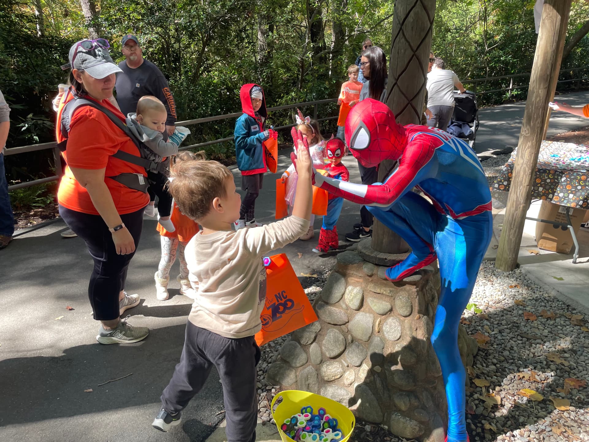 Spider-Man high-fiving a child at an outdoor community event