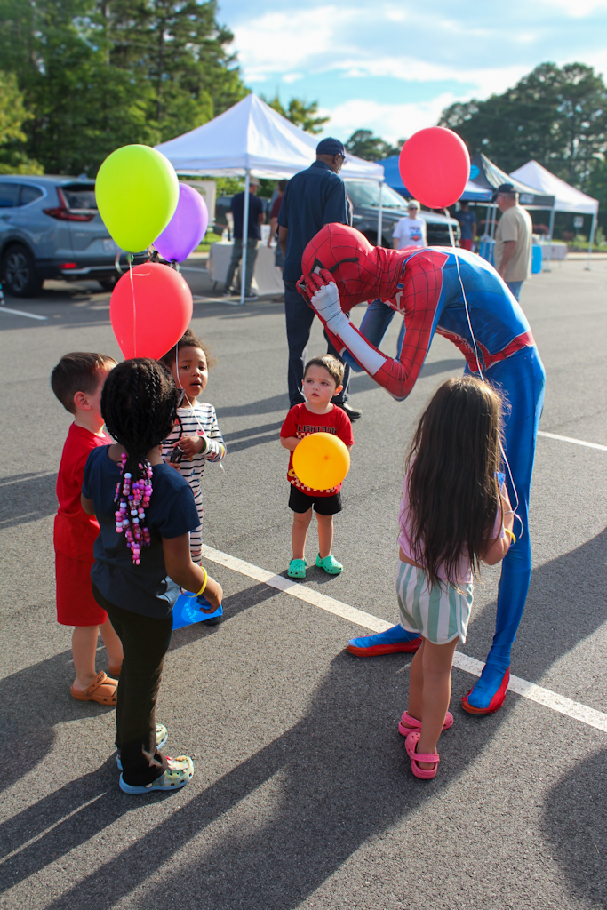 Spider-Man bowing to a group of children holding balloons