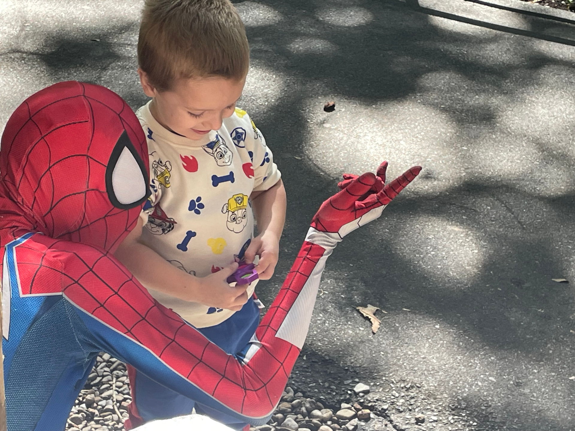 Spider-Man kneeling to talk with a young boy at an event